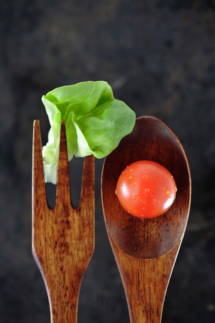 Salatbesteck aus Holz mit Salatblatt & Tomate (Nahaufnahme)