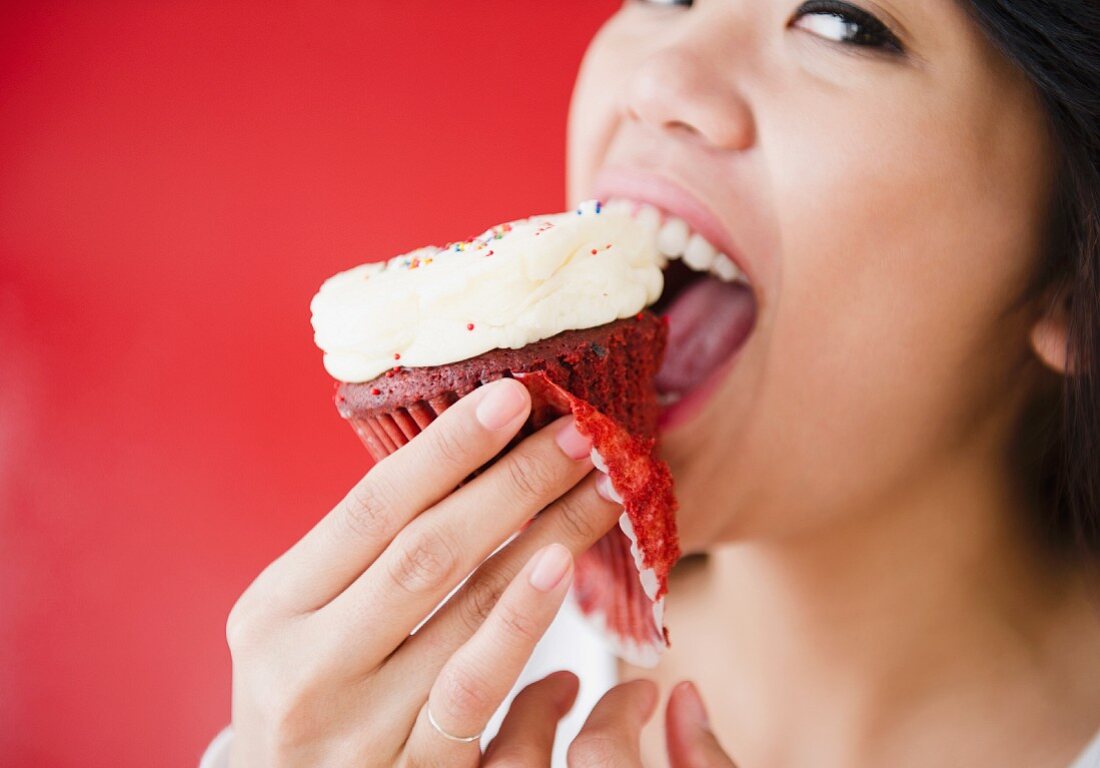 Junge Frau isst Cupcake