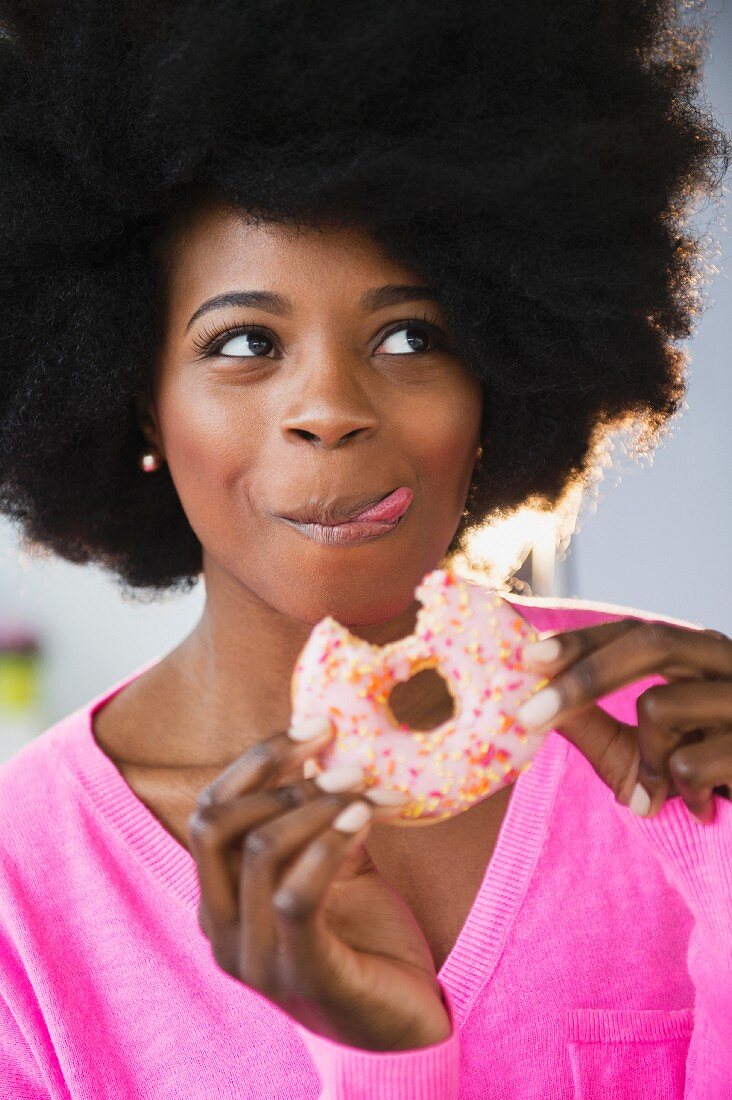 An African-American woman eating a doughnut