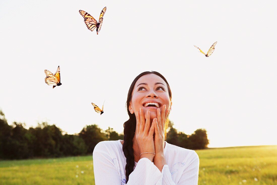 Woman in meadow surrounded by flying butterflies