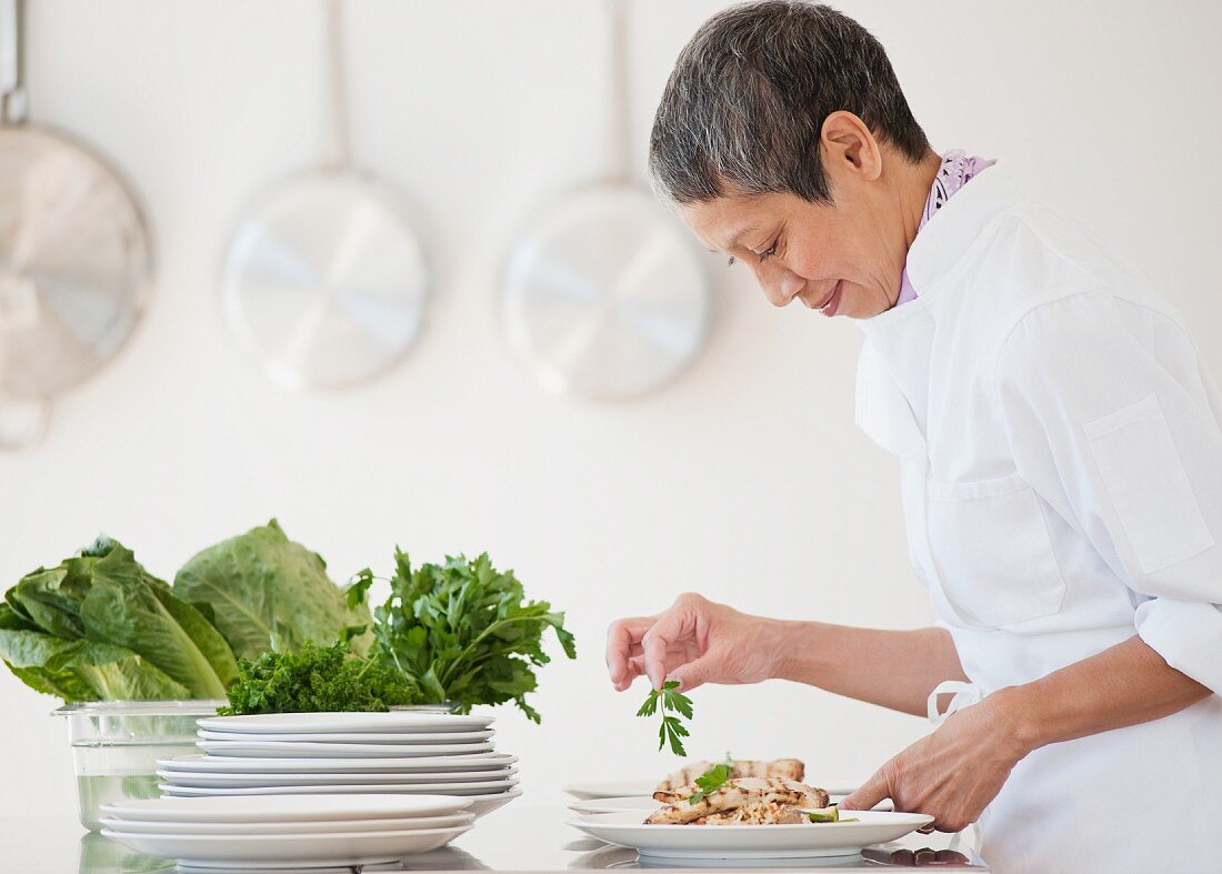 Chinese chef plating meals in professional kitchen
