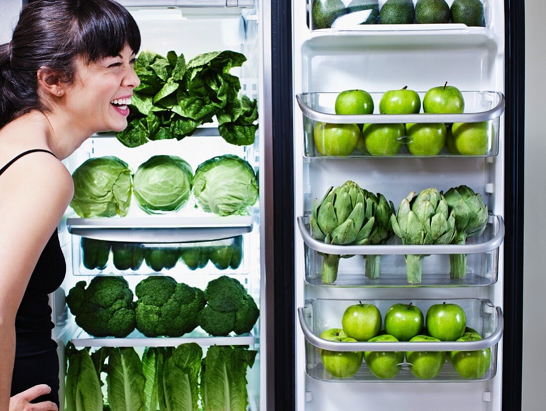 Frau vor Kühlschrank mit grünem Gemüse