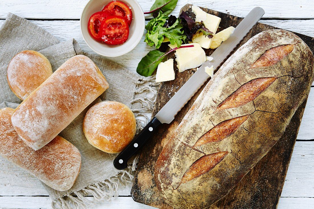 Verschiedene Brote und Brötchen mit Butter, Tomaten und Blattsalat