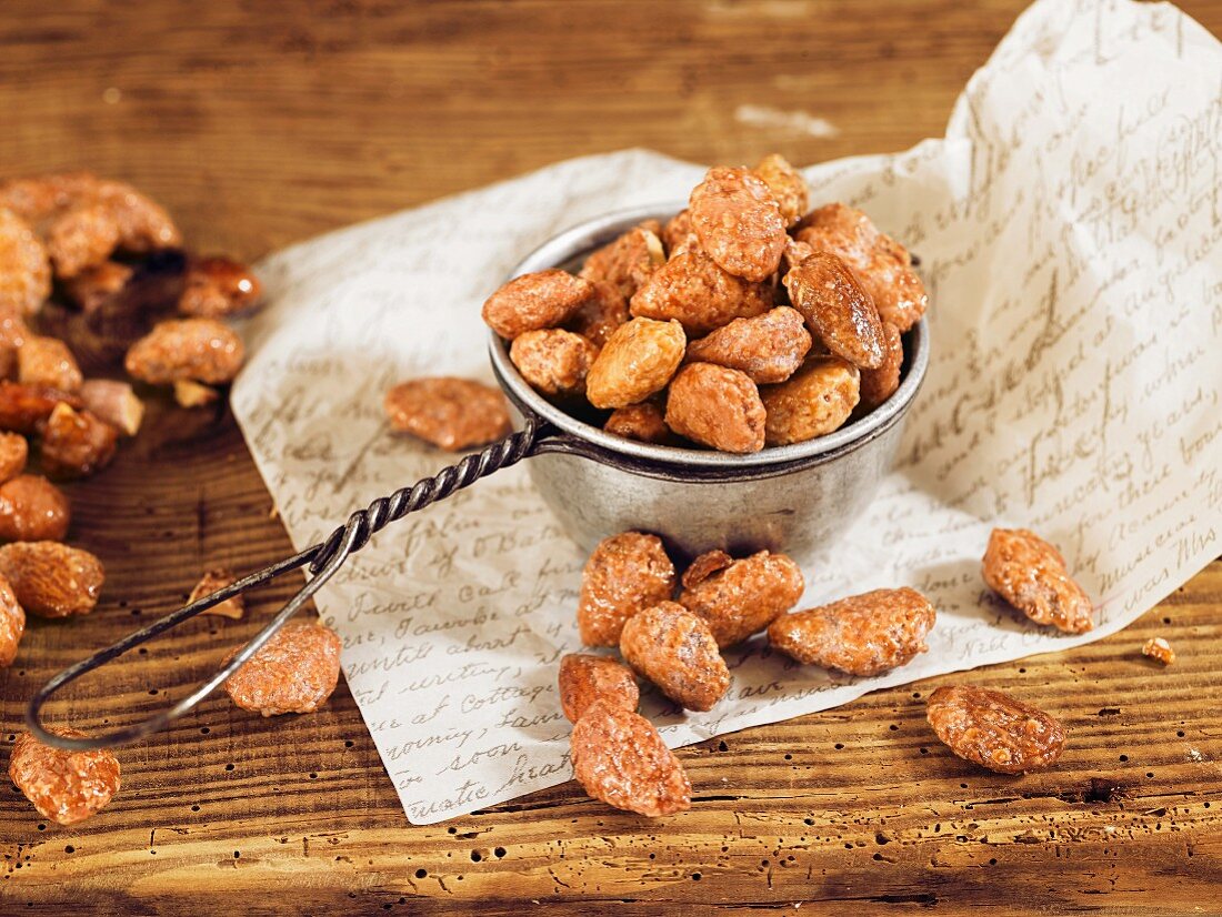 Roasted almonds in a small sieve on a wooden surface