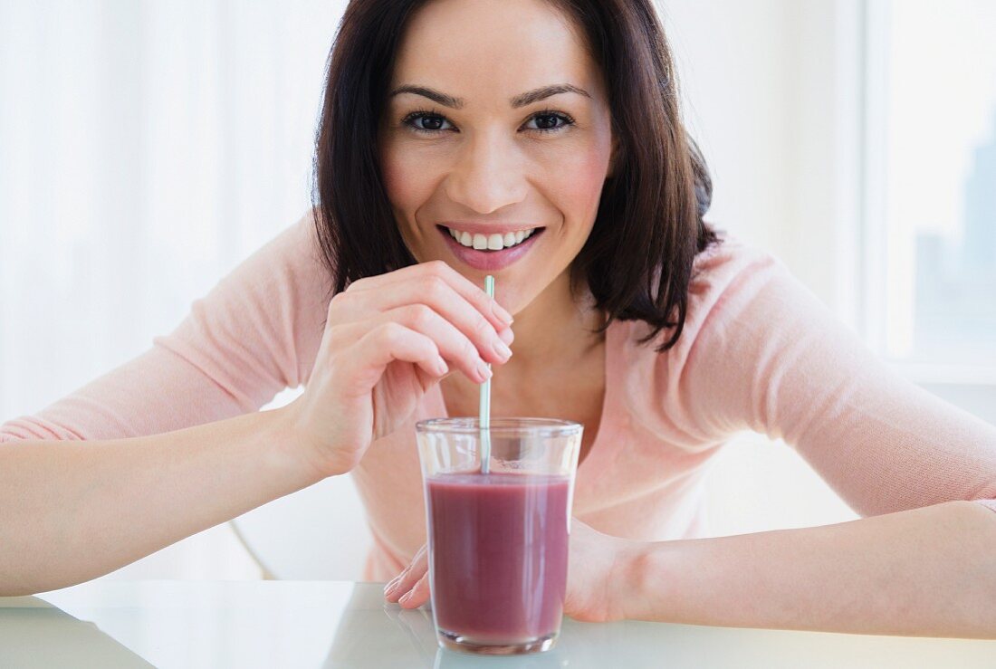 A woman drinking a smoothie through a straw