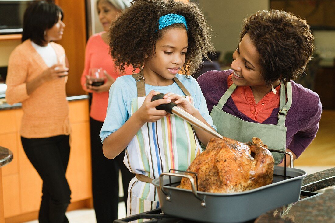 African American girl basting Thanksgiving turkey