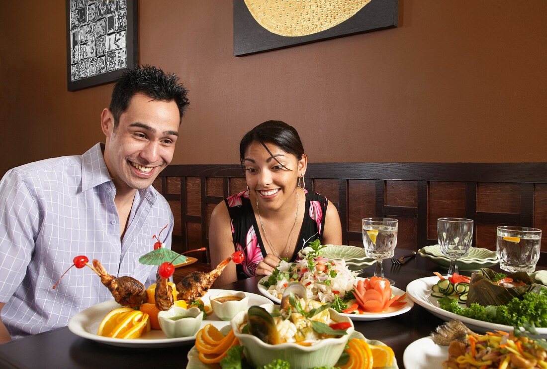 A couple in a restaurant sitting at a table laden with food
