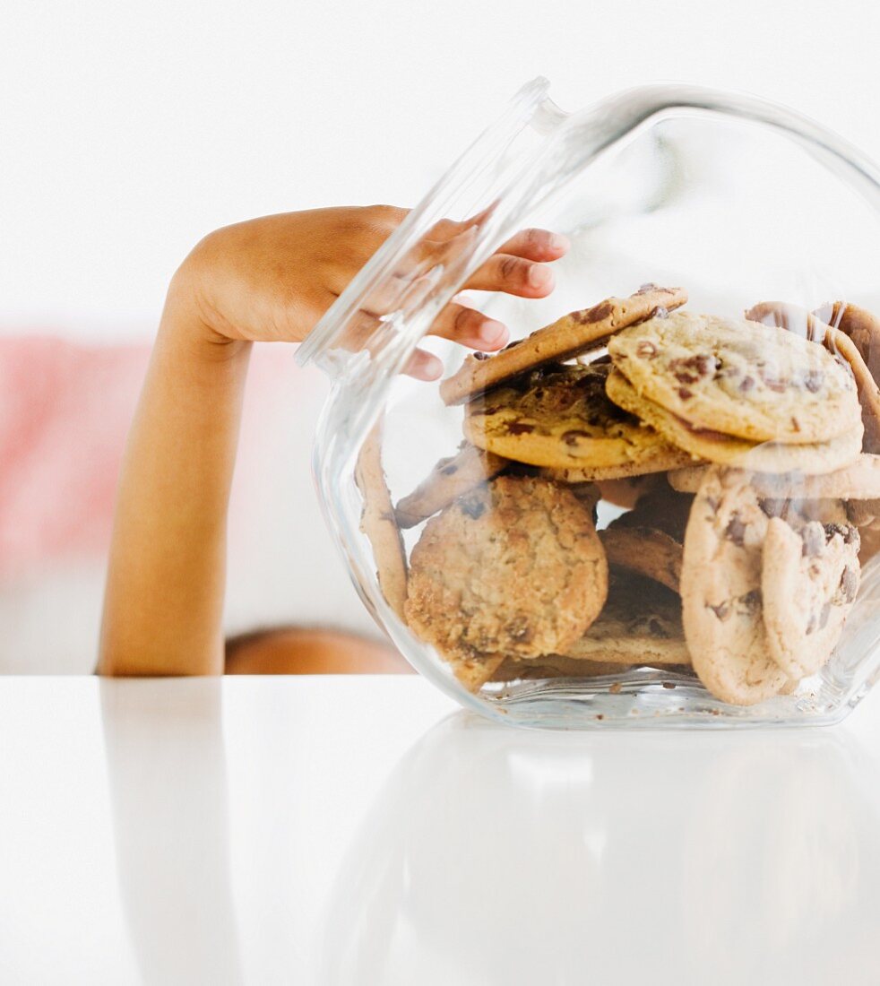 Close up of mixed race girl taking cookie from jar