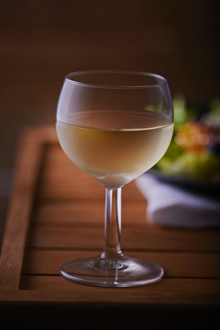 A glass of white wine on a wooden table