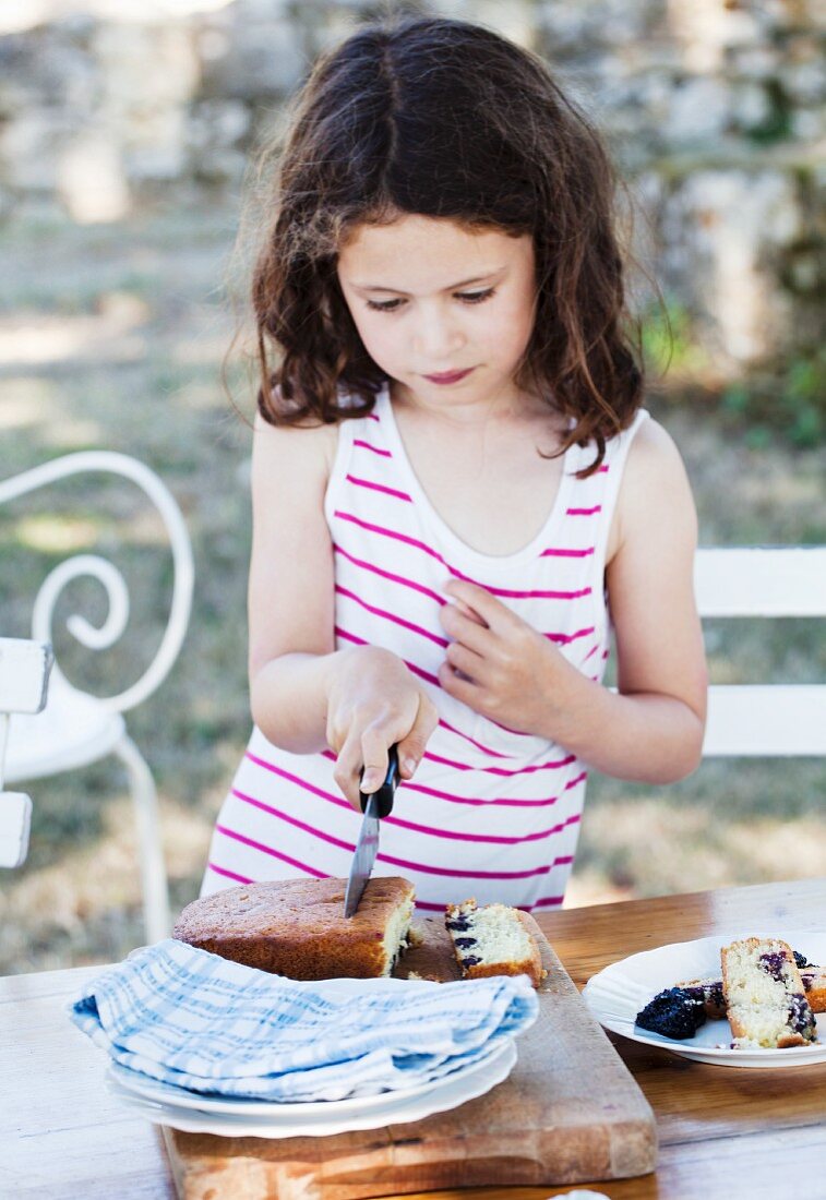 A girl cutting a piece of blackberry cake
