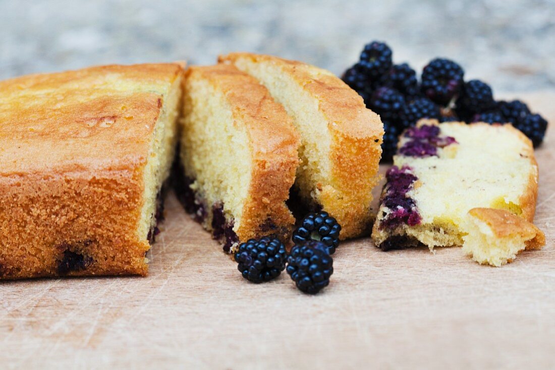 Blackberry cake, partly sliced, on a table in the garden