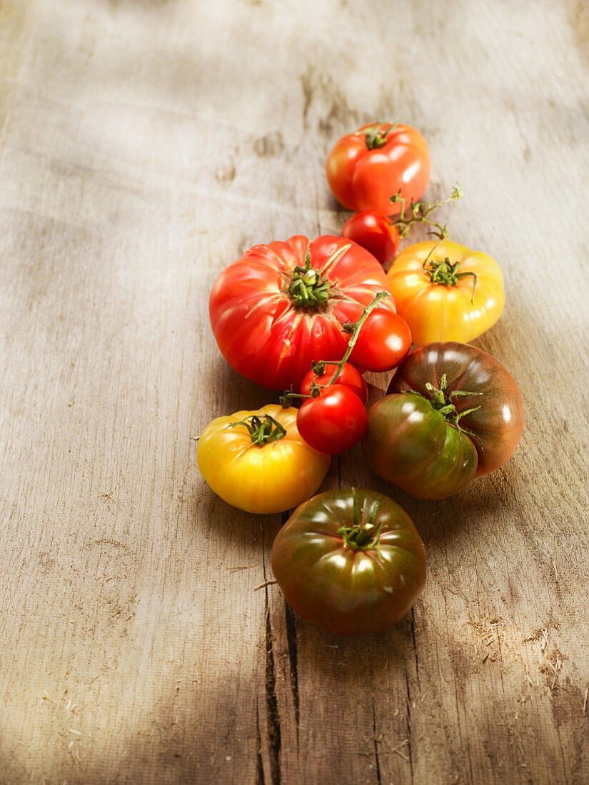 Verschiedene Tomatensorten (Noire de Crimee, Ochsenherz-Tomaten, Ananas-Tomaten) auf Holzuntergrund