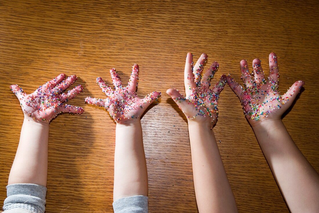 Cookie Sprinkles on Two Children's Hands, High Angle View