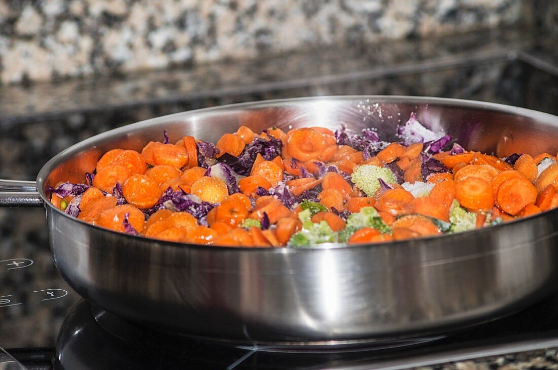 Carrots with red cabbage and broccoli in a frying pan