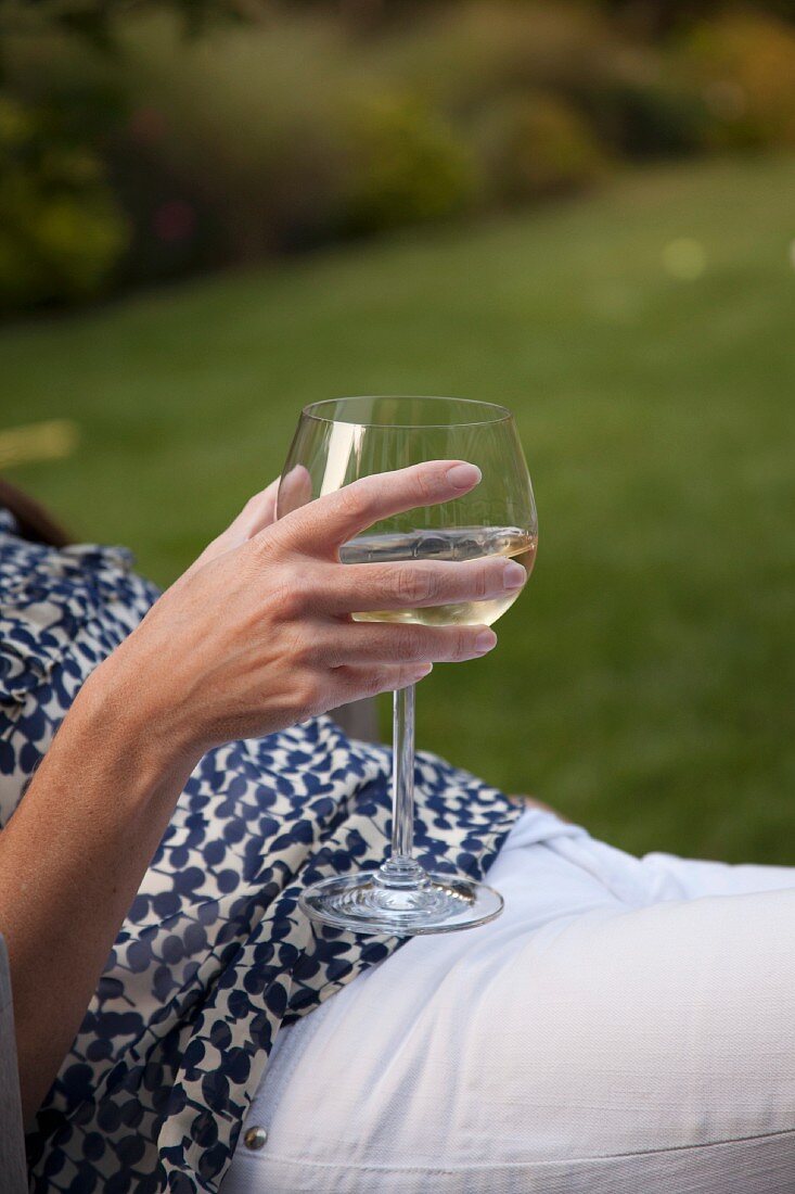 Frau mit einem Weinglas auf der Gartenliege