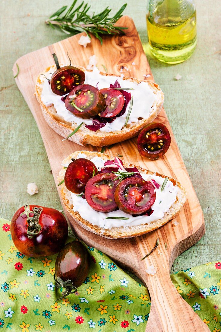 Slices of bread topped with cream cheese and sliced tomatoes