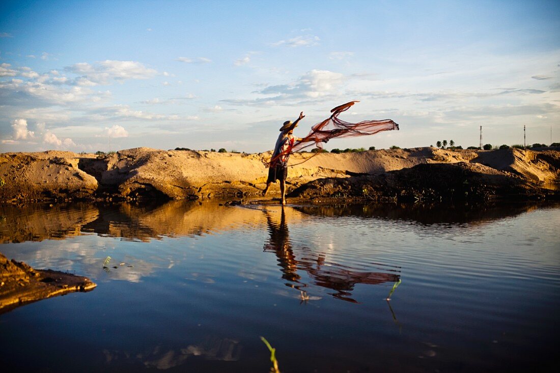 Young Man Tossing Fishing Net into Small Pond, Asia