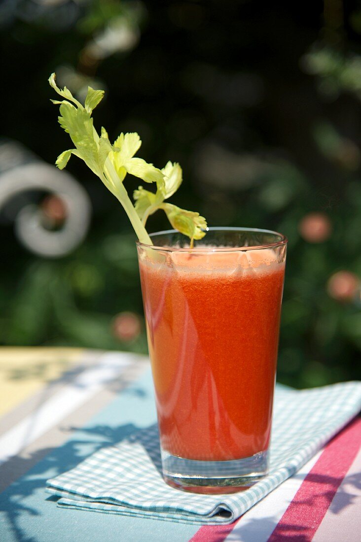 Tomato drink with celery on a table in the garden