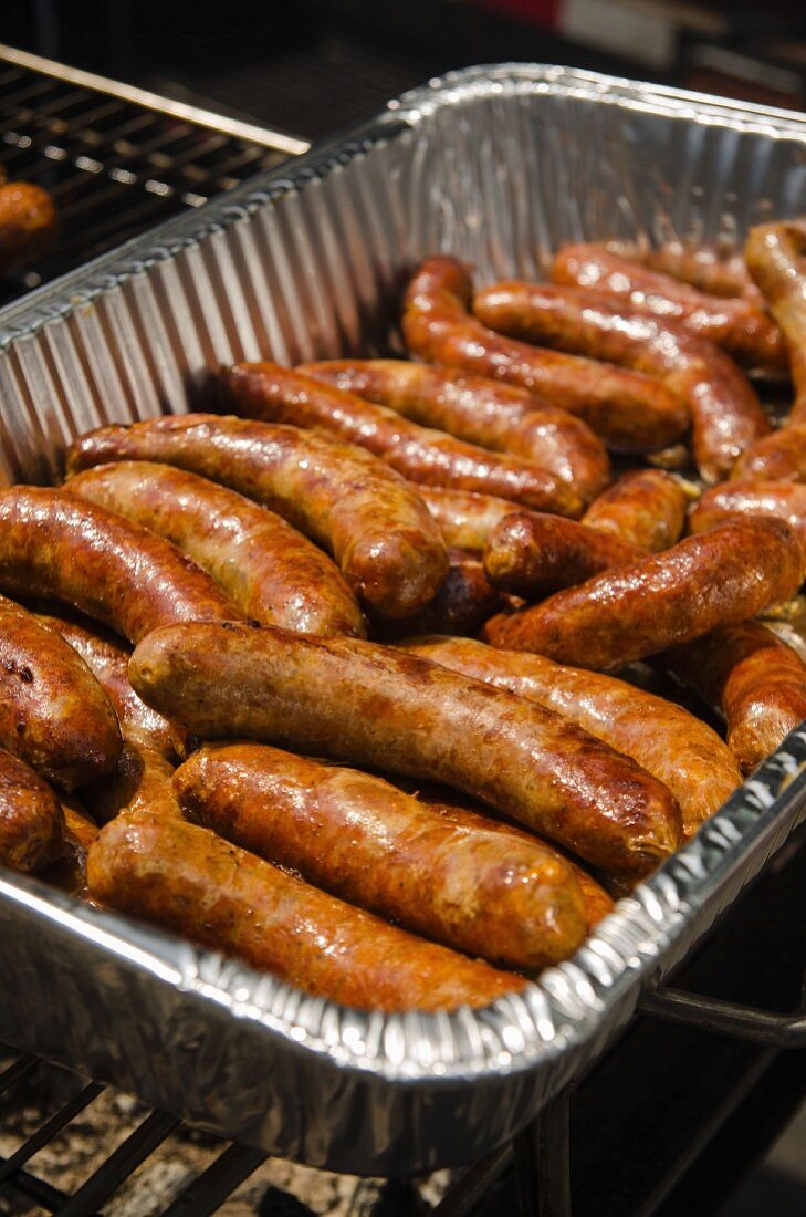 Aluminum Tray of Cooked Sausages on Grill