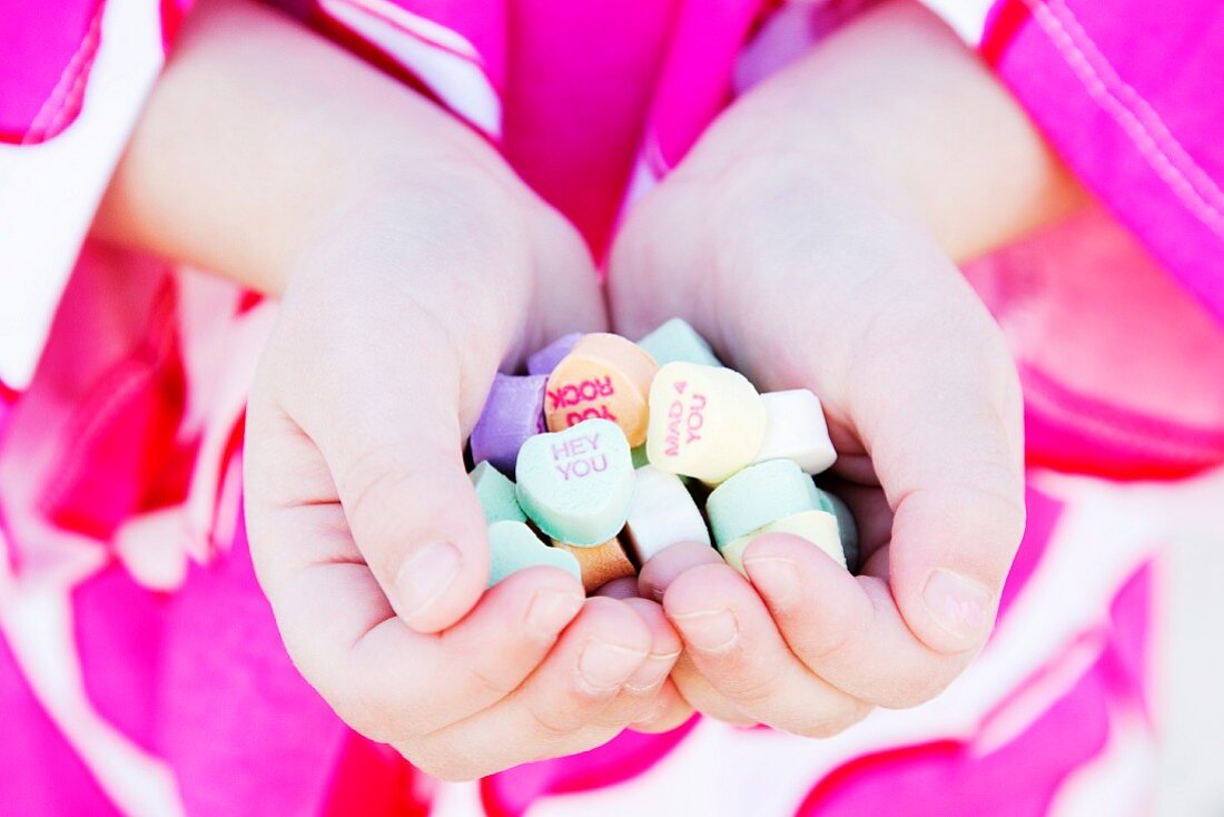 Girl holding heart candy with messages, Close-Up
