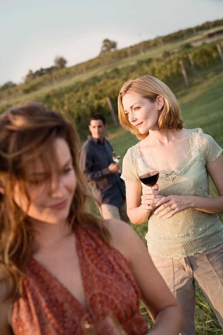 Friends Walking Through Vineyard with Wine