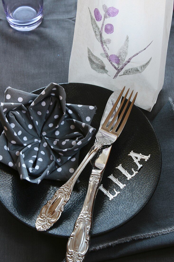 Place setting; napkin folded into lotus flower, tealight in translucent paper bag and letters on plate