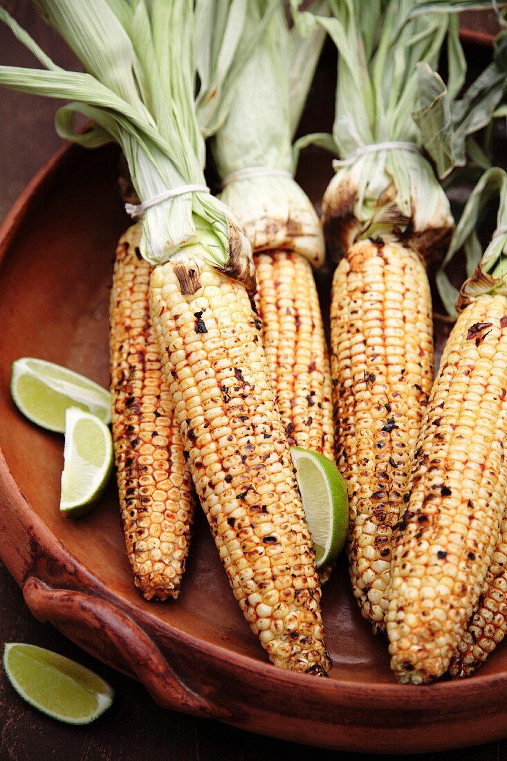 Roasted corn on the cob and limes in bowl