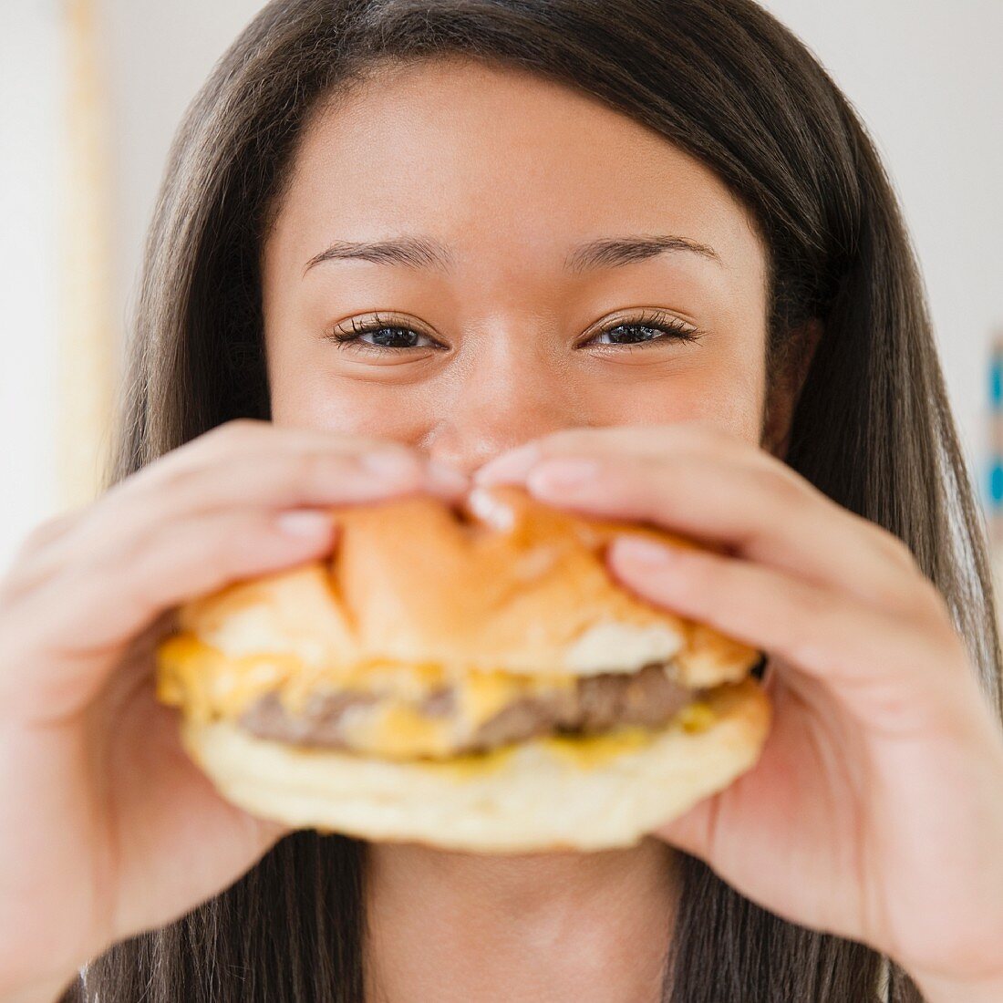 Close up of mixed race teenage girl eating cheeseburger