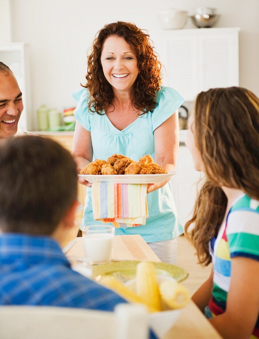 Smiling woman serving family dinner