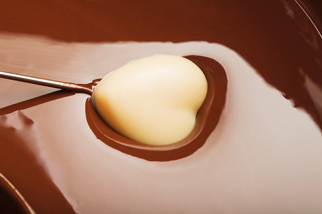 Heart-shaped candy being dipped in chocolate