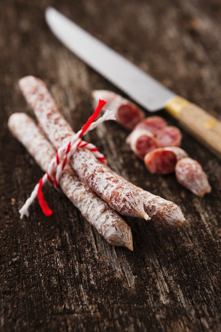 Mini salami on a wooden surface with a knife