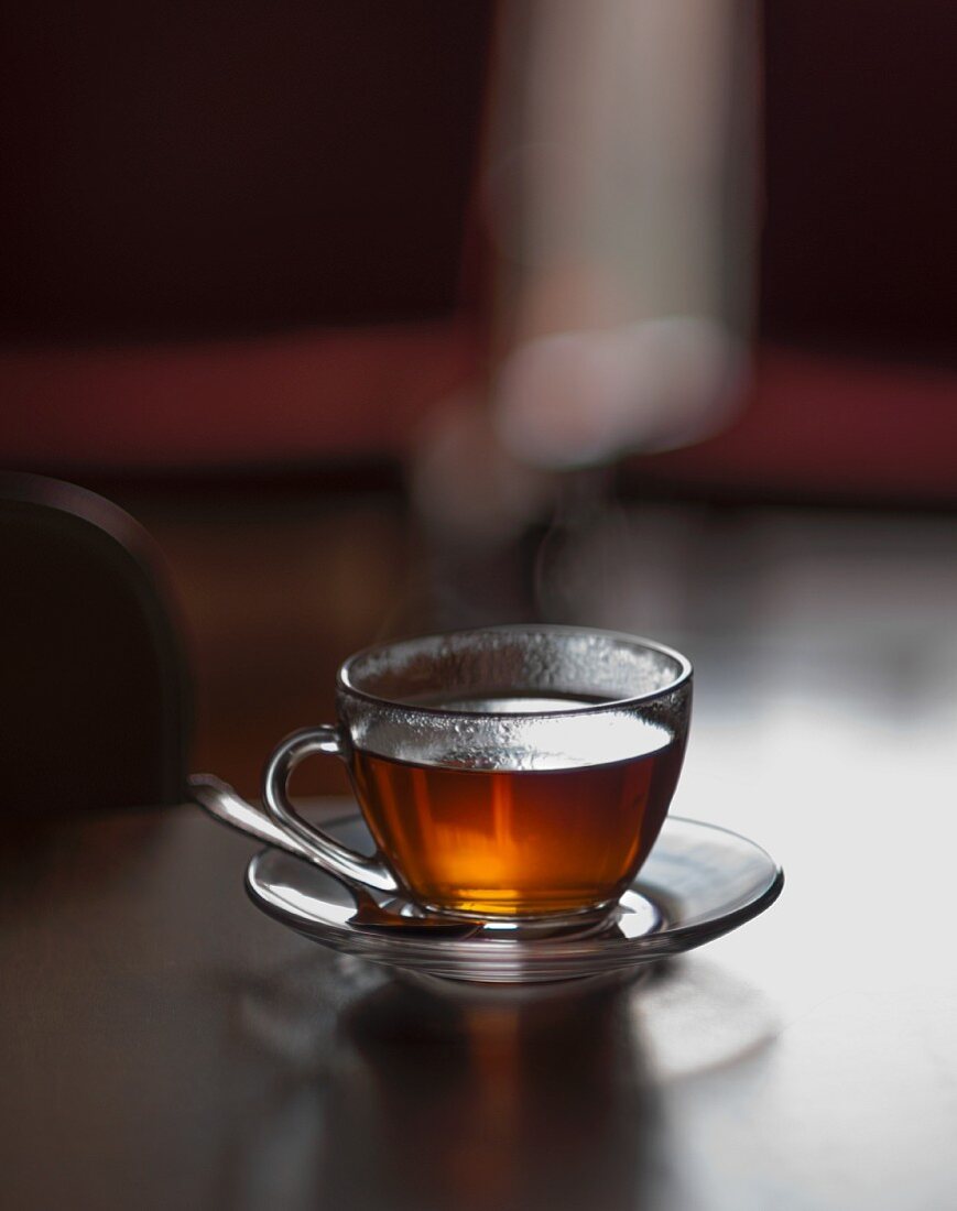 Heisser Tee in Glastasse auf Tischplatte