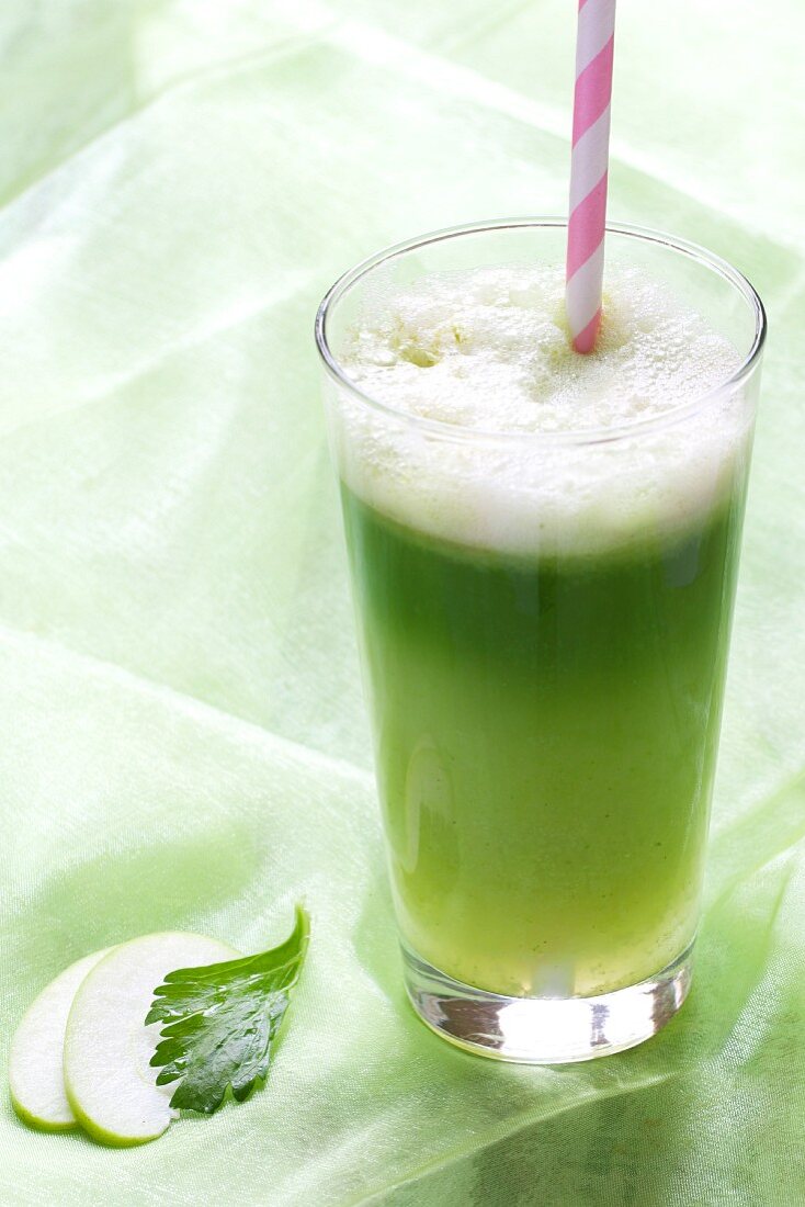 Grüner Vitaminsaft im Glas mit Strohhalm