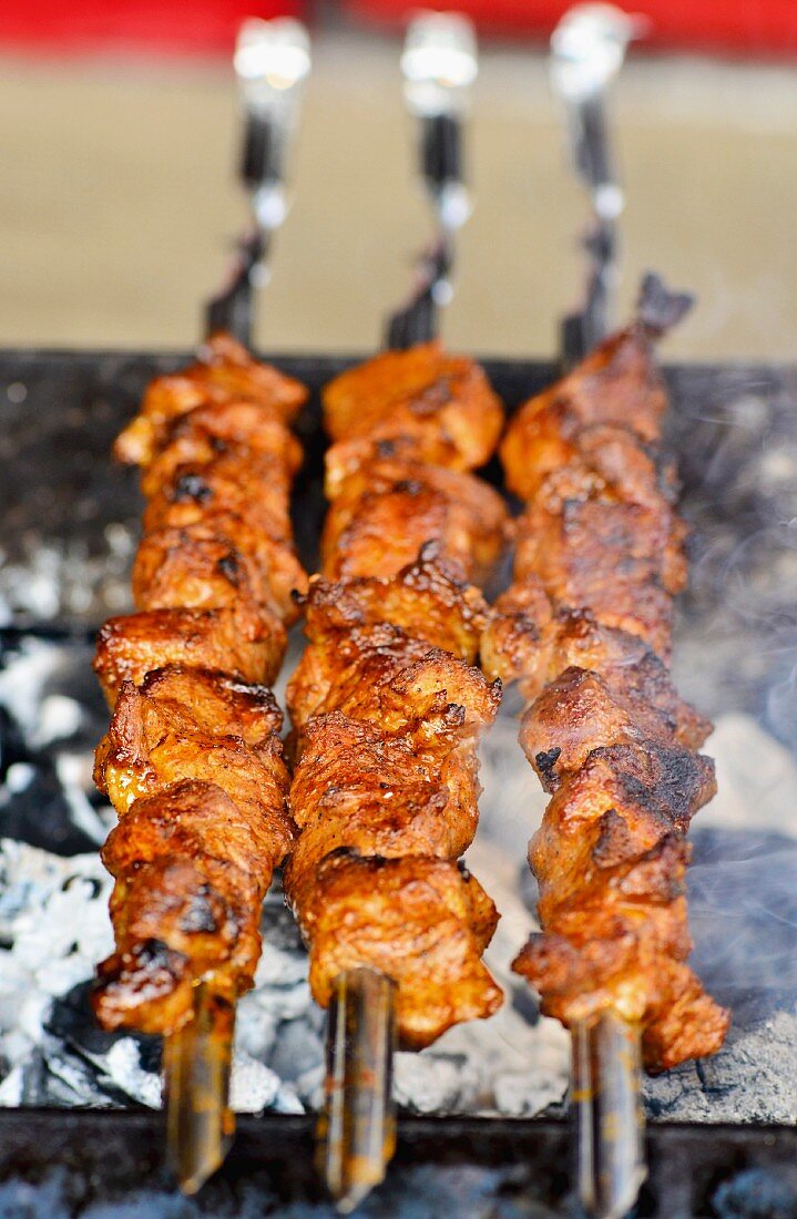 Shashlik kebabs cooking on a charcoal grill