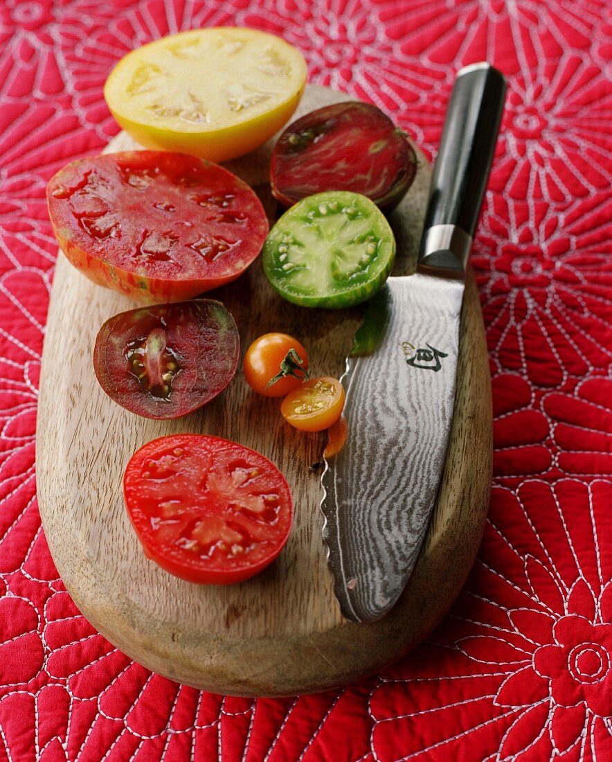 Various halved tomatoes on a wooden board