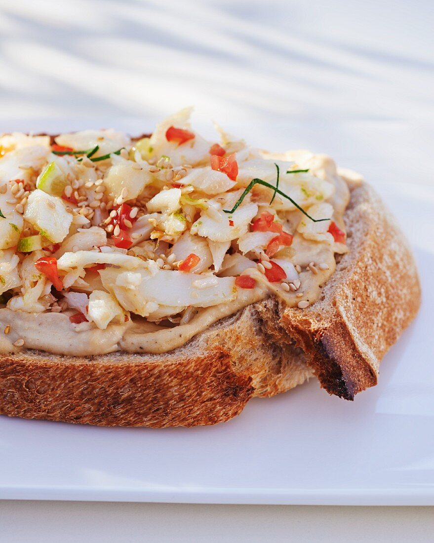 A slice of bread topped with hummus and cod