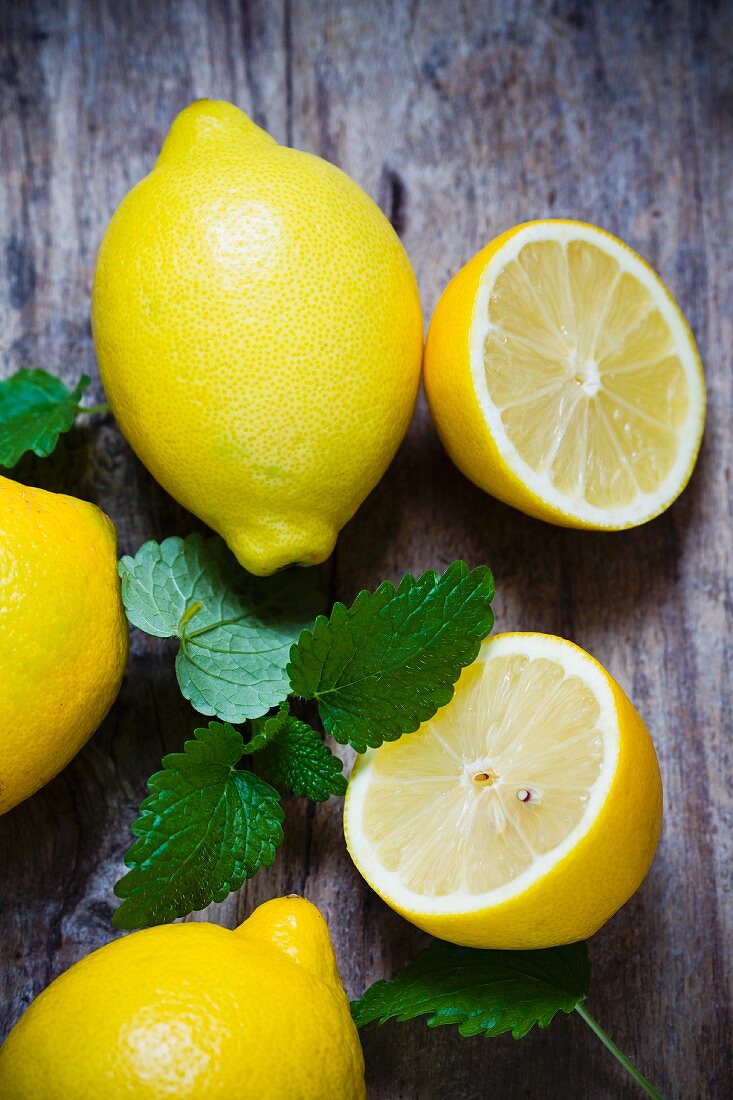 Fresh lemons and lemon balm on a wooden surface