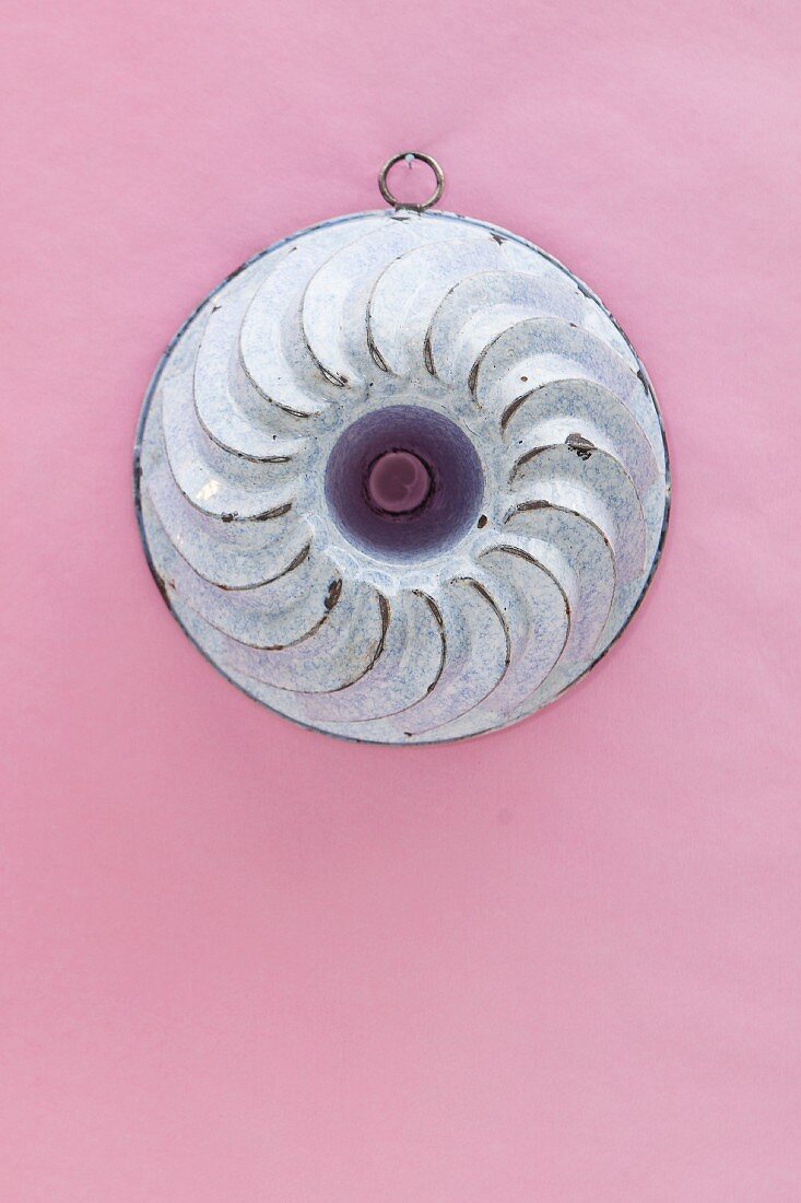 An old Bundt cake mould hanging on a pink wall