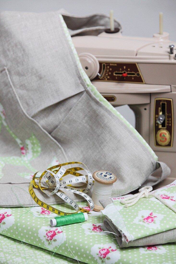 Sewing utensils on floral fabric and hand-sewn cloth bag in front of sewing machine