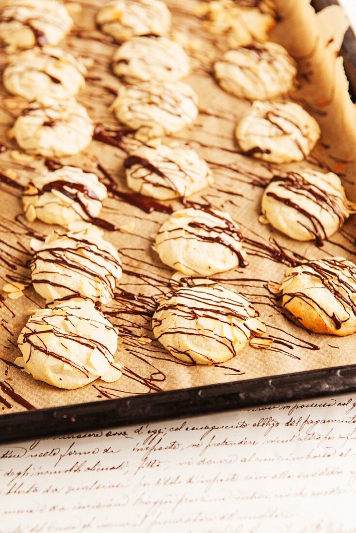 Macaroons drizzled with chocolate on a baking tray