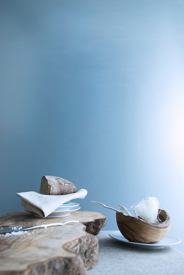 Stylised hunters' breakfast - plate, napkin and bread on rough wooden board next to wooden bowl