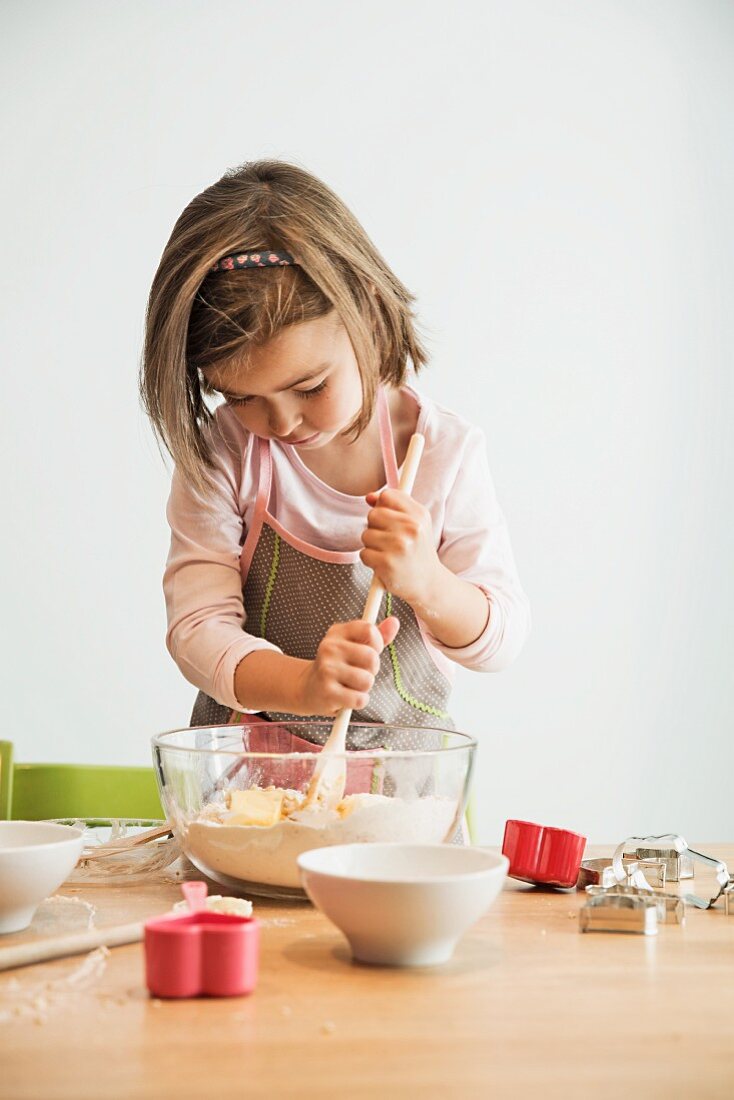 A girl stirring biscuit mix with a wooden spoon