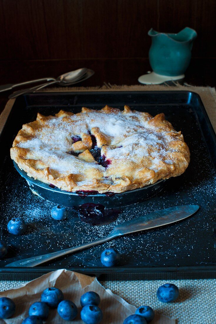 Blueberry Pie on a metal tray with jug of cream and fresh blueberries