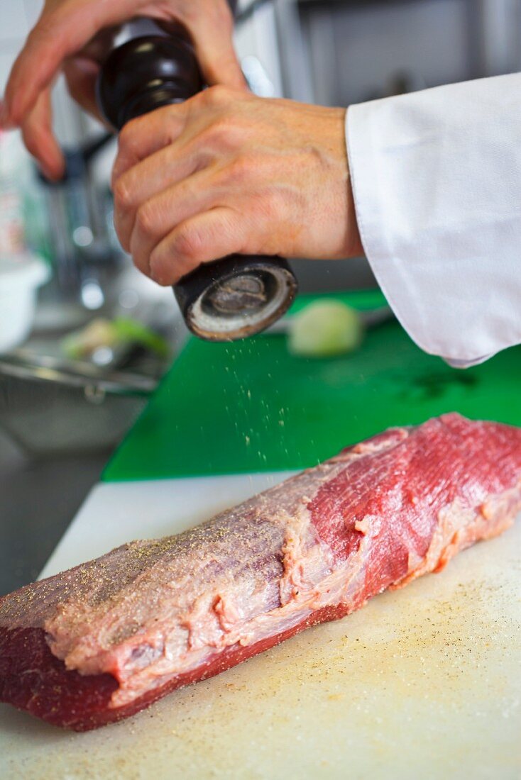 preparation of a typical Czech dish called Svickova, seasoning a tenderloin beef with pepper and salt