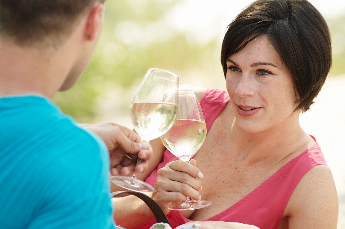 Paar trinkt Weißwein bei einem Picknick am Strand