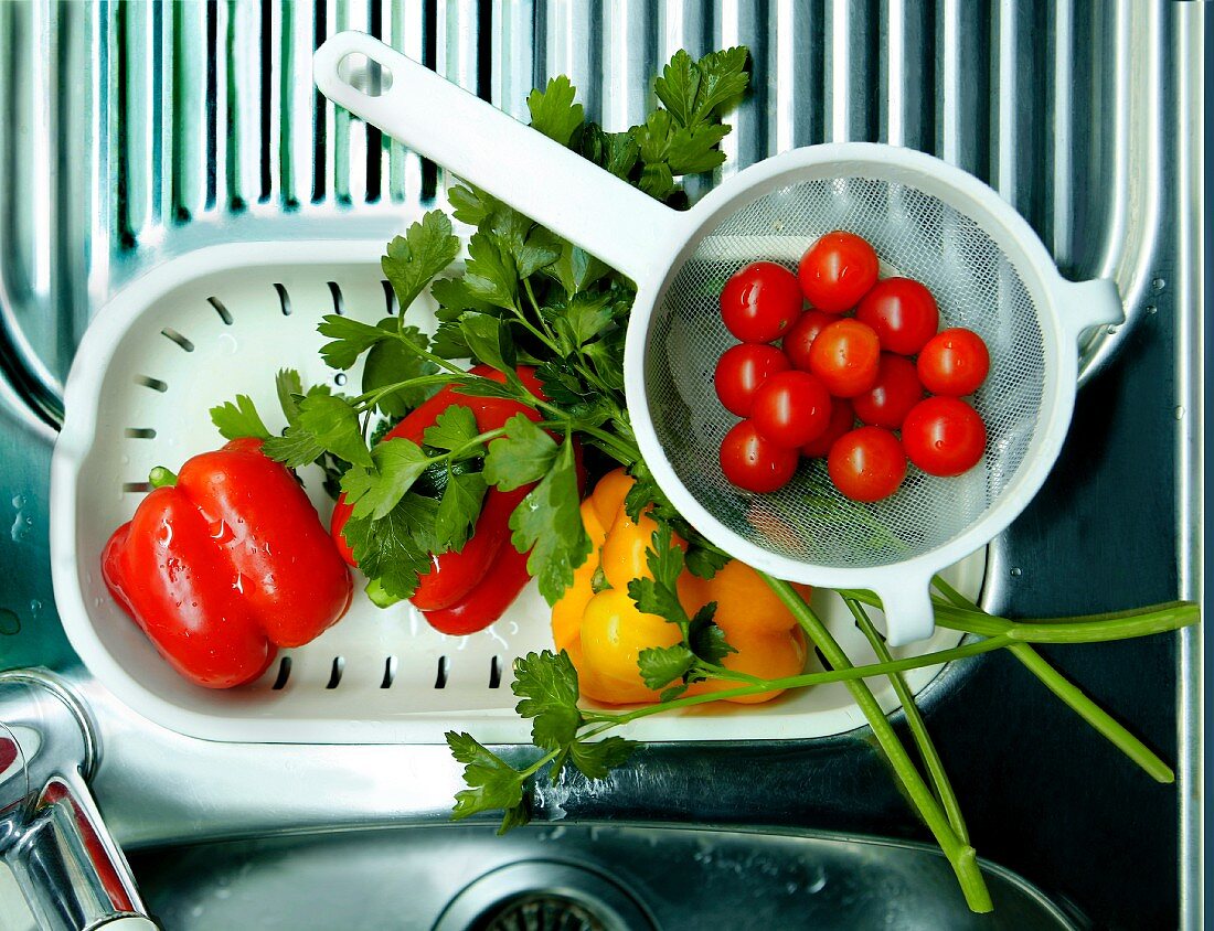 Fresh cherry tomatoes, peppers and parsley on a drainer
