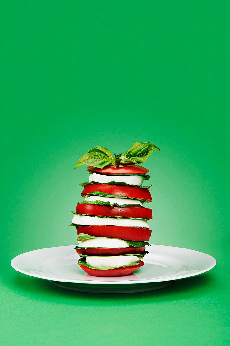 Tomaten-Mozzarella-Turm auf grünem Hintergrund