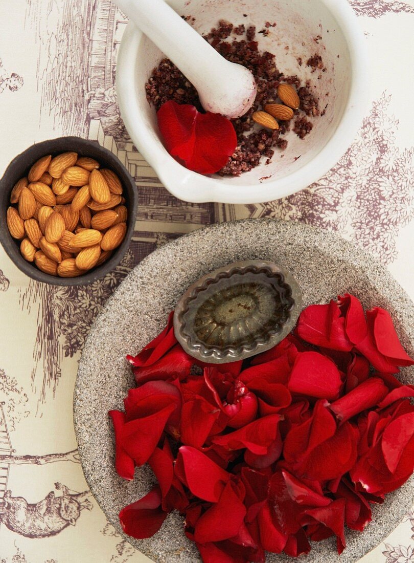 A stone bowl filled with rose petals, a bowl of almonds and a porcelain mortar