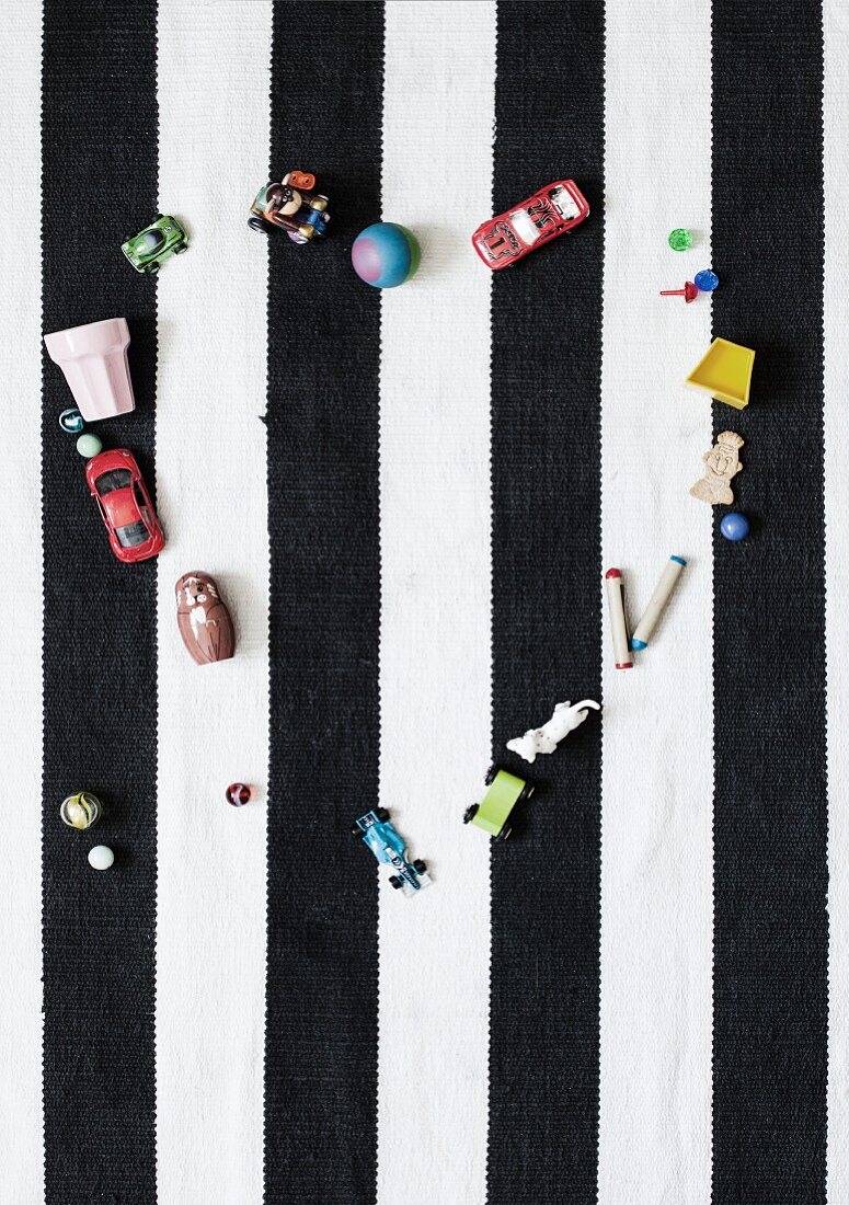 Toys arranged in heart shape on black and white striped rug