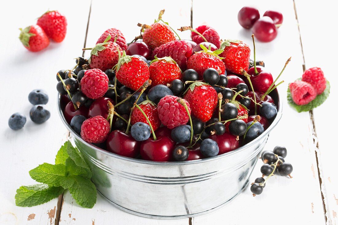 Various red fruits in a metal bucket